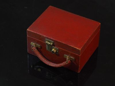 une petite valise rouge posée sur une table noire