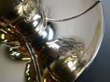 a silver tea pot and a silver spoon on a white plate