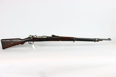 un vieux fusil repose sur une surface blanche, à côté d'une bouteille en verre