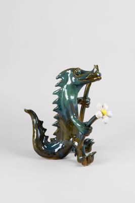 figurine de dragon tenant une fleur dans la gueule, sur fond blanc