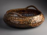 an image of a brown bowl with a handle on a gray surface