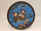 a blue plate with a bird and flowers on it