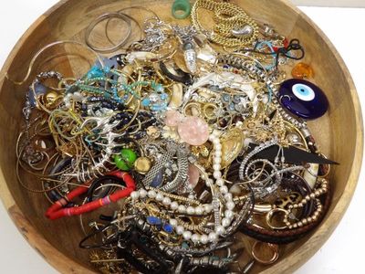 un bol en bois rempli de nombreux bijoux, posé sur une table