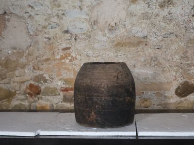 un vase marron posé sur un rebord devant un mur de pierre
