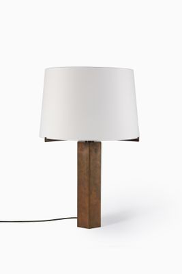 La lampe est en bois et est munie d'un abat-jour blanc.
