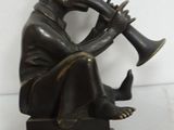 bronze statue of a man playing a trumpet sitting on a pedestal