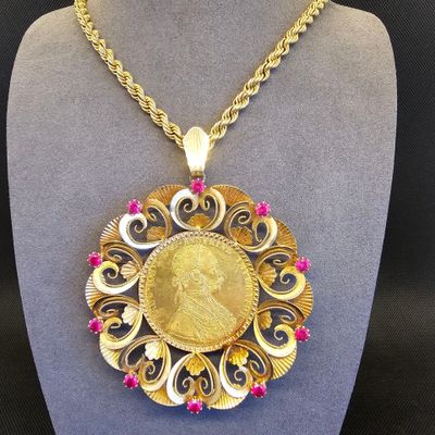 un gros plan d'un collier orné d'une pièce d'or, porté par un mannequin