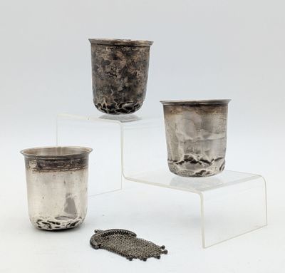 trois coupes en argent posées sur un socle transparent