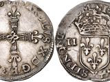 a silver coin with a cross on the front and a crown on the back