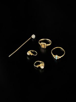 a collection of gold rings and a stick on a black background