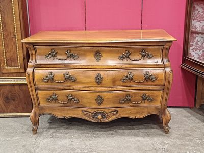 une commode ancienne dans une pièce dont le mur rose sert de toile de fond