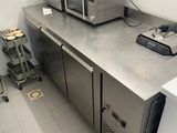plan de travail en acier inoxydable dans une cuisine professionnelle équipée d'un micro-ondes et d'un réfrigérateur