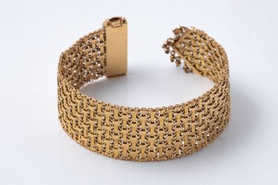 a close up of a gold bracelet on a white surface