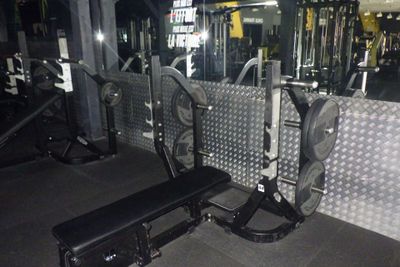 une salle de sport équipée d'un banc, d'haltères et d'autres appareils