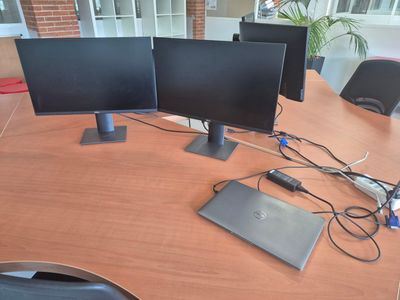 three computer monitors sitting on top of a wooden desk