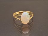 yellow gold ring with a white opal stone on a black surface