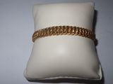 a close up of a gold bracelet on a pillow on a white surface