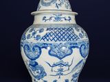 blue and white vase with a bird on top of it on a black background