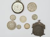 de nombreuses pièces de monnaie et une montre de poche posées sur une surface blanche