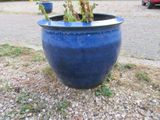 un pot bleu contenant une plante, posé par terre