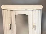 a small white cabinet with a mirror on top of it