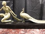 statue en bronze représentant une femme et un paon, posée sur un socle en marbre