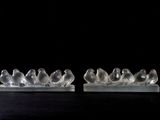 pair of clear glass birds sitting on a marble base