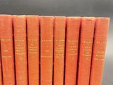 six orange books lined up in a row on a table