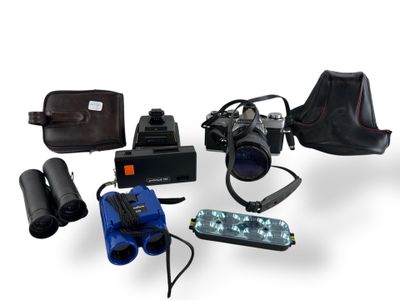 un appareil photo, un étui pour appareil photo, un appareil photo et d'autres objets disposés sur une surface blanche