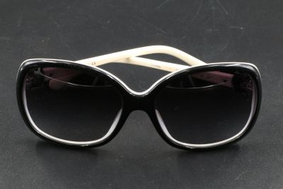 des lunettes de soleil noires et blanches posées sur une table noire, sur fond noir