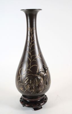un vase noir orné de motifs dorés, posé sur un socle