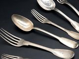 five silver spoons and two silver spoons on a black table