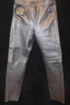 un pantalon en cuir argenté accroché à un mur noir