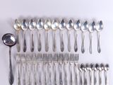 un grand nombre de cuillères et de fourchettes en argent disposées sur une table