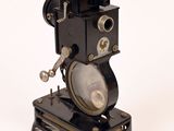un appareil photo à l'ancienne posé sur un trépied, sur une surface blanche