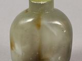 a small glass bottle with a green top on a white surface