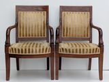 two wooden chairs with striped upholstered seats against a white wall
