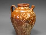 a brown vase with designs on it on a gray surface