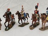 five figurines of soldiers riding horses on a white surface