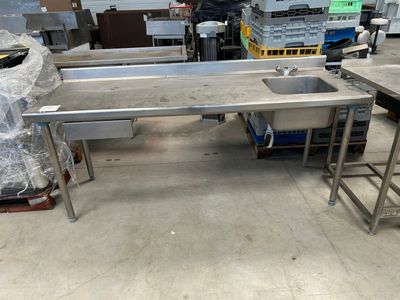 tables de travail et éviers en acier inoxydable dans un entrepôt, avec des palettes en arrière-plan