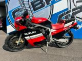 une moto rouge et noire garée devant un panneau bleu et blanc