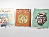 trois livres posés sur une table avec un vase, et un vase posé sur un socle