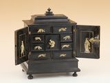 une commode noire et dorée dont la porte est ouverte