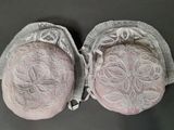 une paire de genouillères roses ornées de dentelle blanche, posées sur une table