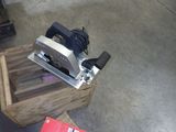 Quelqu'un utilise une raboteuse pour couper un morceau de bois posé sur une table.