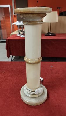 un socle blanc posé sur un tapis rouge dans une pièce