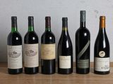 several bottles of wine are lined up on a wooden table