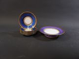 two blue and white plates with gold rims sitting on a black surface