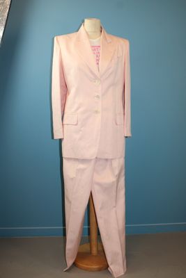 un costume rose posé sur un mannequin devant un mur bleu