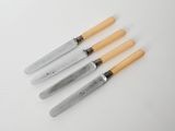 a set of four knives with wooden handles on a white surface